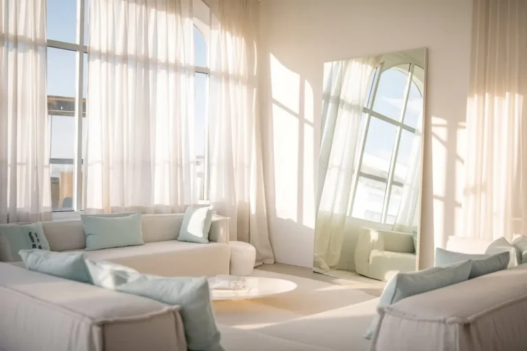 A bright, airy living room with soft natural light streaming through large windows, featuring a minimalist white and light blue color palette. Modern, lightweight furniture with clean lines, a large frameless mirror reflecting sunlight, and sheer white curtains creating a sense of openness and tranquility. High-resolution, professional interior design photography style, soft and inviting atmosphere.